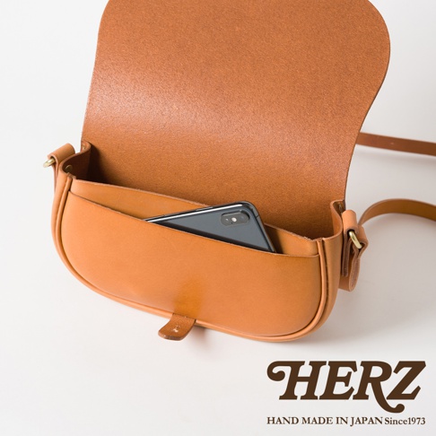 職人手作皮革迷你馬鞍包，採用棕褐色皮革製成，包身飽滿，翻蓋設計，內側可放入一支手機。