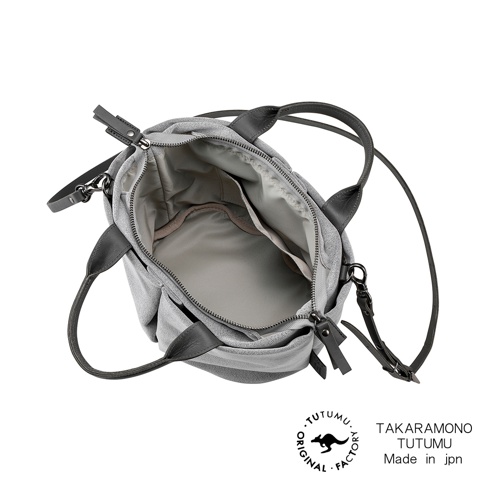 TUTUMU 品牌 Suede Marche petit 兩用單肩包，灰色絨面材質，以俯視角呈現，包內織物夾層清晰可見，附有可拆卸肩帶，底部有 TUTUMU 原創工廠的標誌及 Made in jpn 字樣。