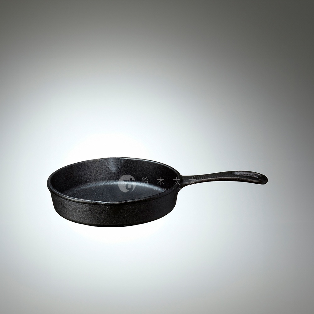 一個黑色的 18 公分鑄鐵平底鍋，帶有長柄。