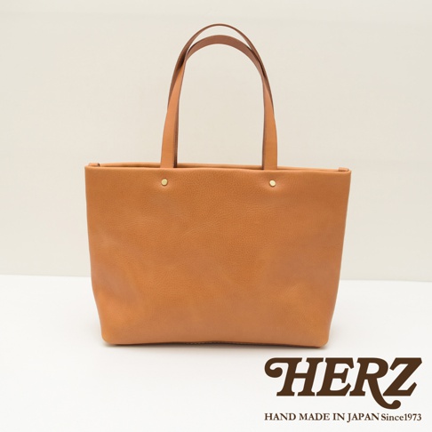 職人手作皮革4口袋極簡托特包T-3，採用淺棕色皮革製成，設計簡潔，配有兩條皮革提把和兩個金屬鉚釘裝飾。