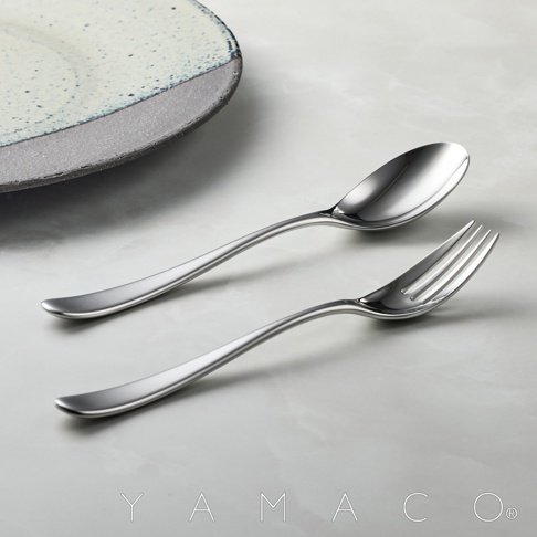 霧面不鏽鋼叉匙兩件組，搭配部分盤子，置於淺灰紋理桌面。