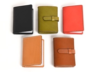 五款職人手作皮革卡片收納夾，分別為黑色、橄欖綠、紅色、淺棕色與深棕色。皆為皮革材質，設計簡約，部分款式附有皮革綁帶。