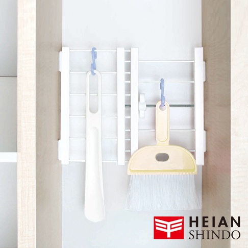 圖片右下角有HEIAN SHINDO品牌標誌，左側掛著一隻白色長柄鞋拔，右側掛著一個黃色小畚箕和刷子，它們都掛在一個白色的伸縮縫隙置物架上。