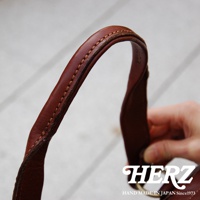 棕色皮革迷你波士頓包提把，縫線細緻，展現職人手作質感，水洗加工皮革紋理自然。