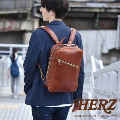 職人手作皮革長方型後背包，深棕色皮革，設有拉鍊主袋和前置拉鍊口袋，金色拉鍊。