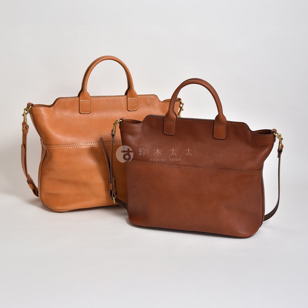 兩只皮革托特包，一個為淺棕色，另一個為深棕色，皆有提把和斜背帶。