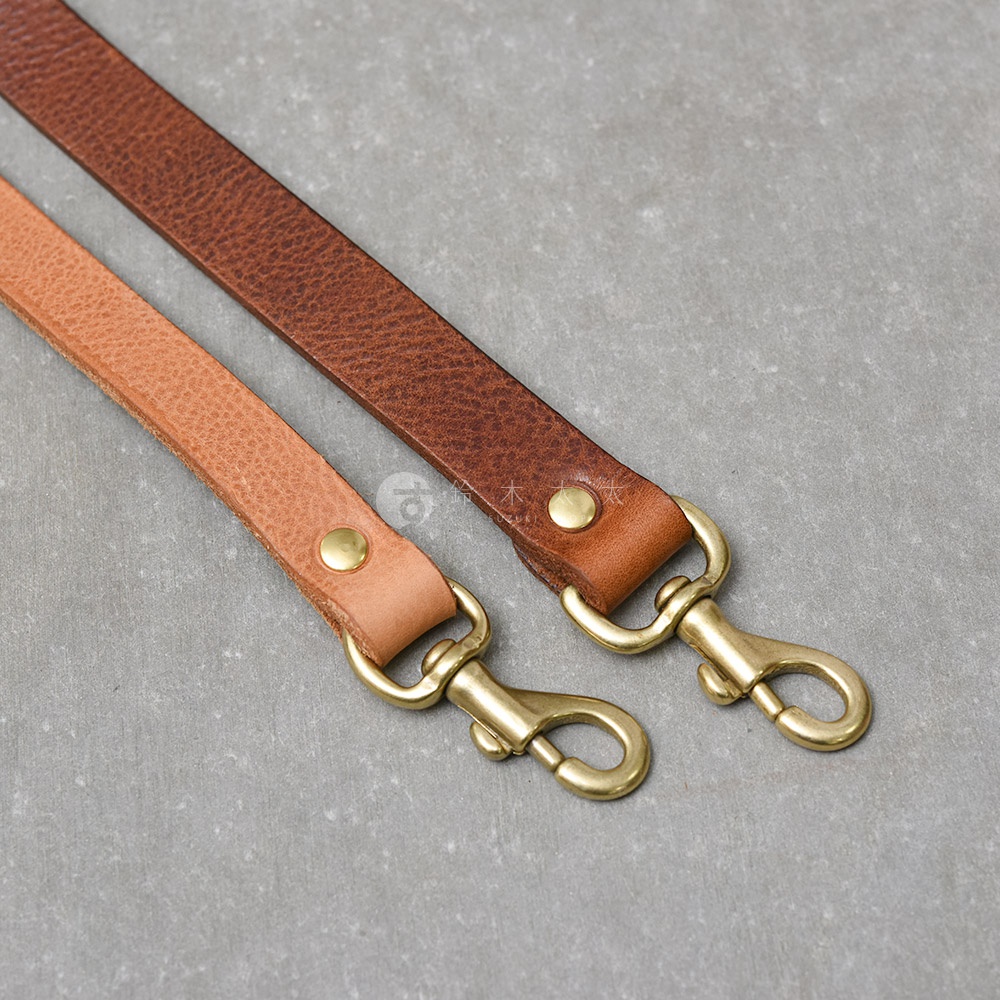 兩個皮革製的提把，一個淺棕色，一個深棕色，都配有黃銅色的掛鉤。