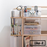 木製書架上擺放著透明可疊式收納盒，內有CD、DVD、遊戲光碟、筆、遙控器、遊戲手把、筆記本等物品。