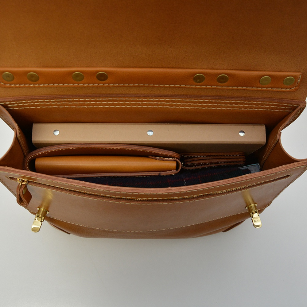 職人手作皮革旅行商務兩用波士頓包，展示打開的包內部，可見棕褐色皮革材質，裝有筆記本、皮夾及格紋布料。