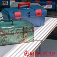 藍色塑膠雙層工具箱，配有紅色提把和紅色鎖扣。前方一個綠色金屬工具箱，表面有明顯的舊化和刮痕，配有金屬提把和鎖扣。