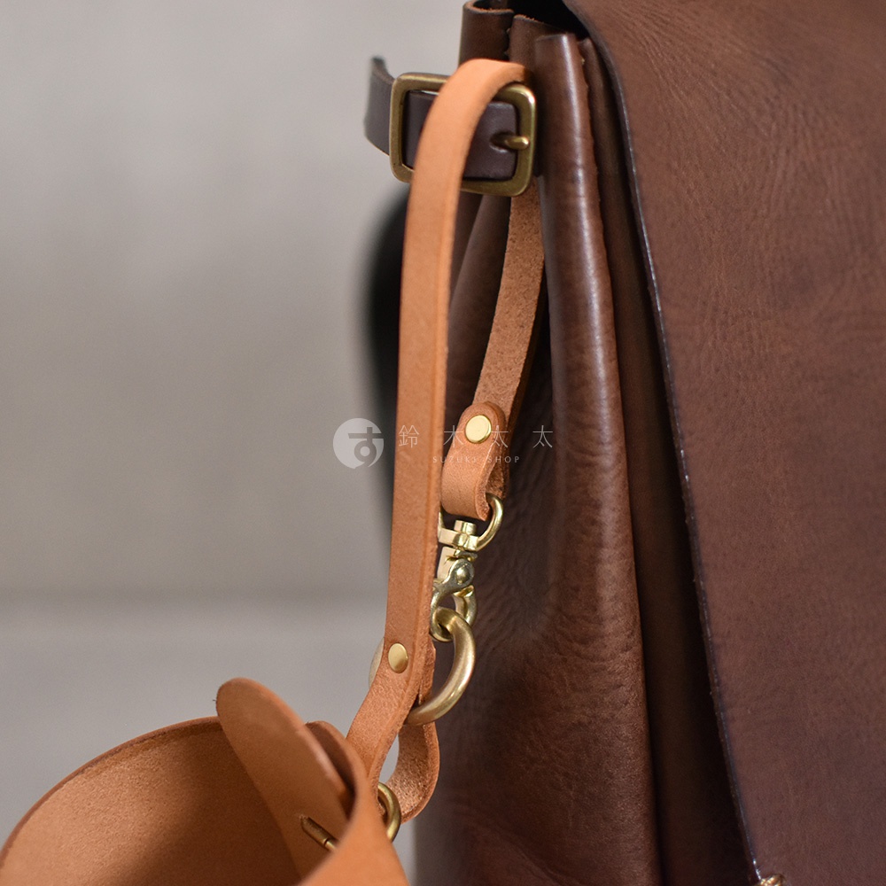 職人手作皮革Organ水壺套，深棕色皮革主體，搭配淺棕色皮革提帶與鉤扣，以及黃銅色金屬配件，展現簡約質感。