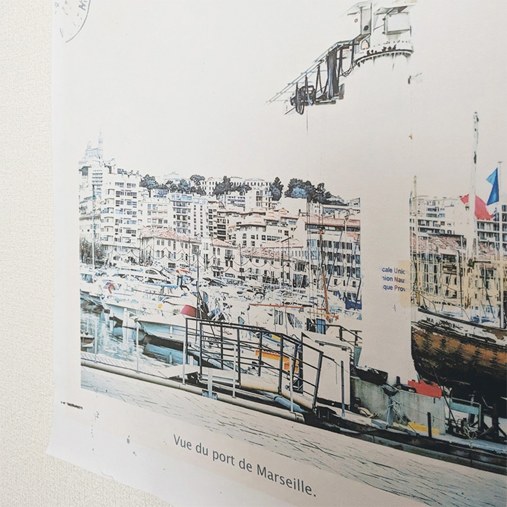 無框帆布藝術海報，描繪馬賽港口景象。畫面中有密集的建築、停泊的各式船隻、藍色旗幟，以及一架飛機的剪影。整體色調以白色、藍色、紅色為主，呈現港口活力。