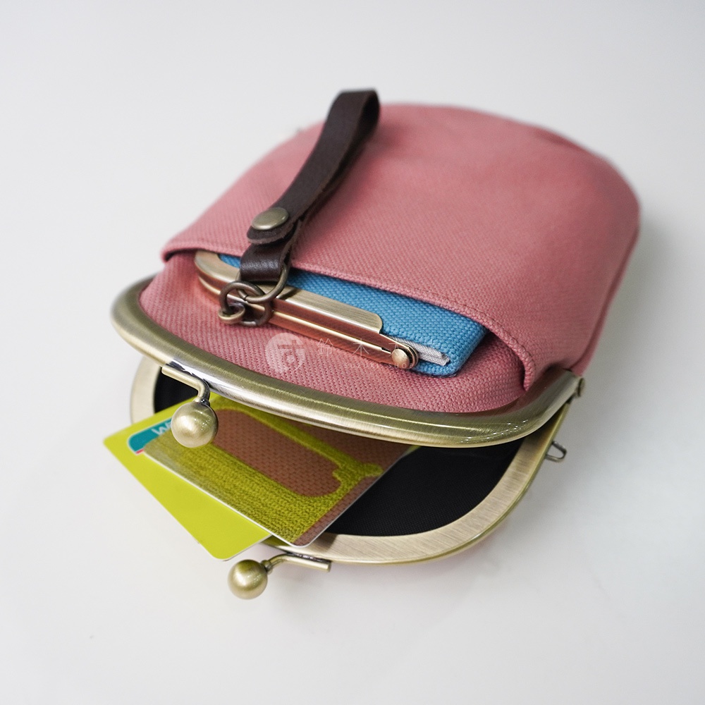 京都職人手作純棉帆布腰掛口金包，露出粉色帆布包身，包內裝有藍色小包和兩張卡片，金屬開合處有皮繩裝飾