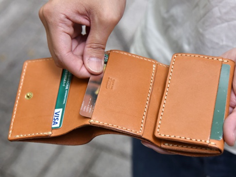 職人手作皮革三折式迷你短夾，溫潤的淺棕色皮革，簡約設計，內有卡槽，展示放入的信用卡和卡片，縫線精緻。