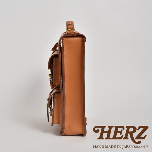 職人手作皮革三口袋三用後背包，側邊視角，展示淺棕色皮革材質、雙層前袋設計及金屬扣環。