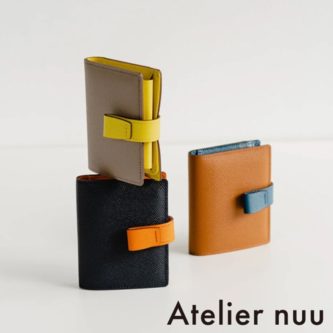 Atelier nuu 品牌 logo 下方展示三個色彩鮮豔的皮革短夾，一個疊在另一個上方，其中一個獨立擺放。
