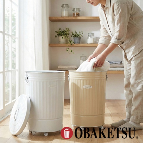 OBAKETSU 附輪垃圾桶，其中一個為米白色，另一為駝色，有人手正將毛巾放入駝色垃圾桶內。