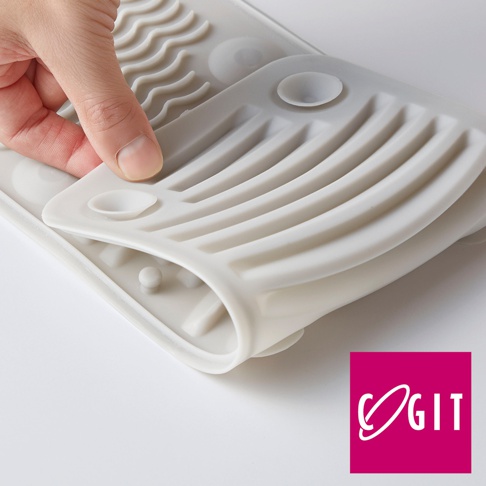 COGIT 品牌的灰色矽膠多功能軟式洗衣板，特寫畫面展示了手部輕柔按壓洗衣板的細節，背景為白色。