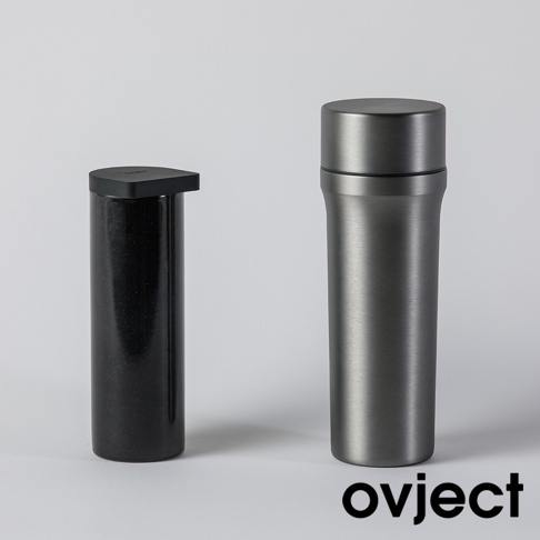 兩個三用保溫瓶，一個為黑色、帶有細緻斑點紋理的圓柱體，頂部配有黑色方形扁平蓋；另一個為銀灰色金屬材質，瓶身光滑，頂部有圓形瓶蓋，整體設計簡約。