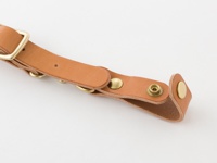 職人手作皮革背包用減壓胸前扣帶 (KO-2)，淺棕色皮革材質，搭配黃銅色金屬扣具，包括調節扣、D型環及按扣，設計用於連接背包肩帶，增加穩定性。