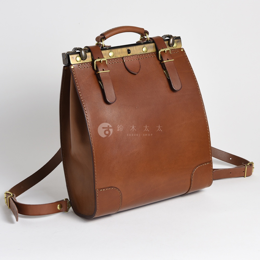 棕色皮革復古口金後背包，配有銅色金屬扣環和兩個皮革束帶。