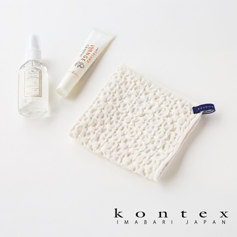 白色棉麻混紡方巾，表面有明顯的鬆餅紋路，一角帶有藍色標籤，旁邊有一支白色噴霧瓶和一條白色軟管。