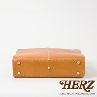 淺棕色皮革雙口袋兩用商務公事包，包身結構簡潔，四角設有金色銅釘，呈現職人手作質感。