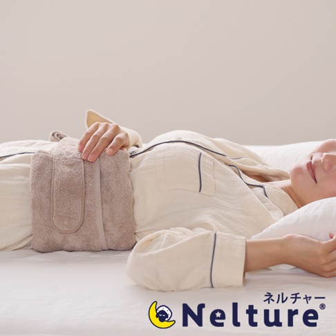 一位女性側臥，腰間繫著一個淺棕色、毛巾材質的可調式睡眠包腰枕。