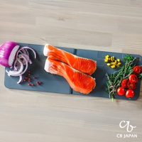 CB JAPAN atomico 系列可掛摺疊砧板（深灰），上面擺放著兩塊鮭魚菲力、切片紅洋蔥、一些番茄和香草，以及切塊的黃色食材。