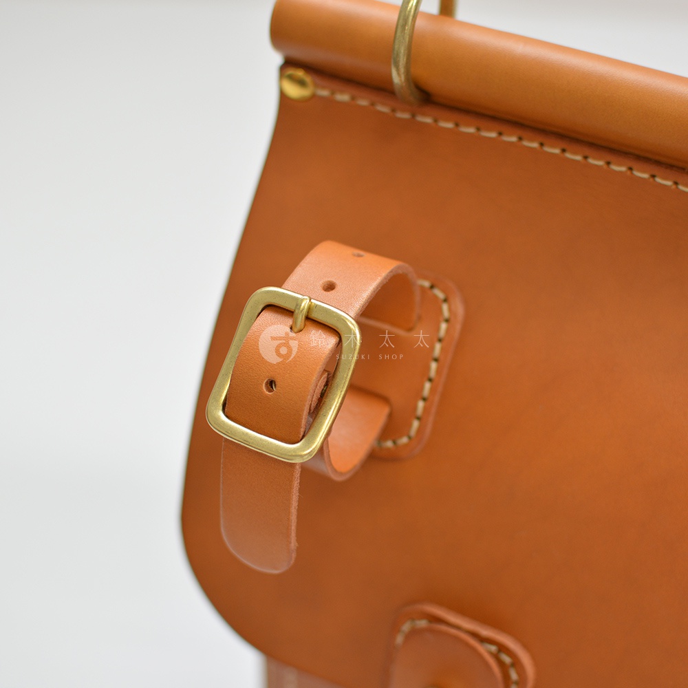 職人手作皮革旅行包A-102，展示了品牌標誌性的原色皮革材質，帶有金屬釦環和縫線細節，呈現簡約復古的風格。