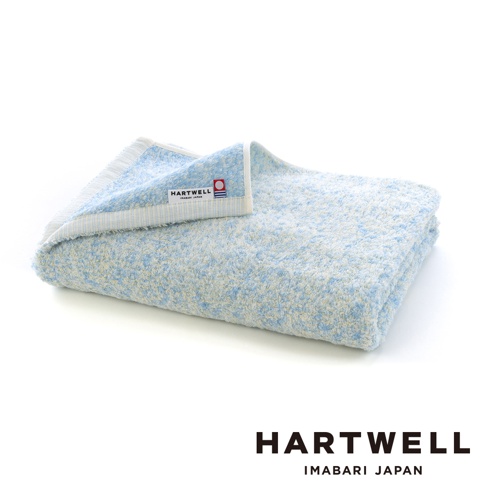 摺疊好的 Hartwell 今治棉質浴巾，表面呈現藍色與白色交織的繽紛混色紋理，邊緣縫有品牌標籤，整體質感柔軟舒適，背景為純白色。