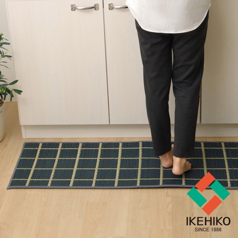 藺草榻榻米廚房地墊，深藍色底紋搭配米黃色網格紋，材質觸感明顯，長方形平鋪於木質地板上，靠近廚櫃。