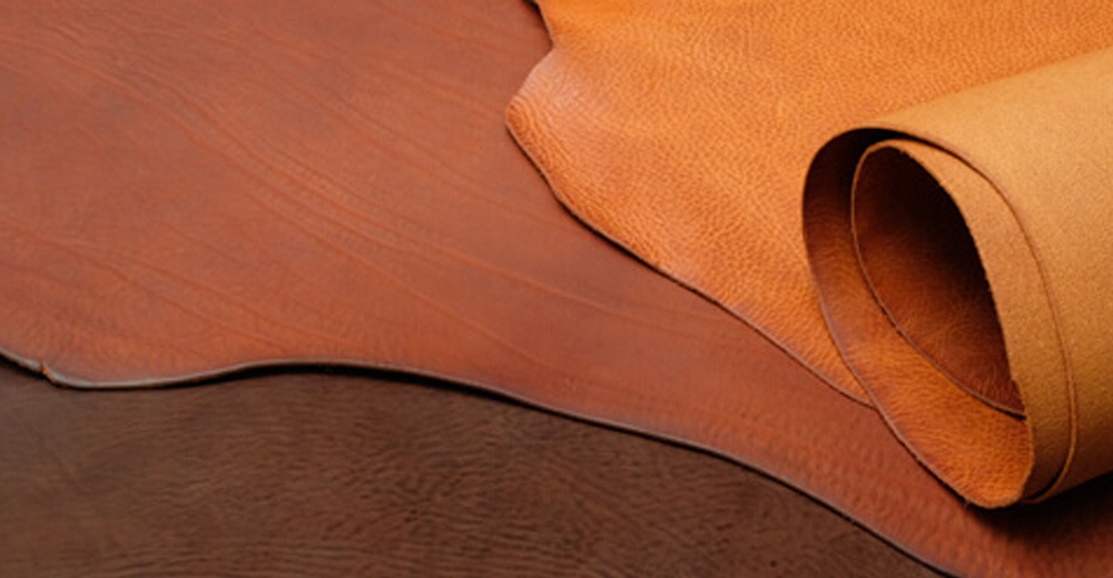 職人手作皮革Organ水壺套，展示兩種顏色：溫暖的棕色和淺棕色皮革。皮革表面帶有自然的紋理，其中一塊皮革捲起，呈現出柔軟的質感。