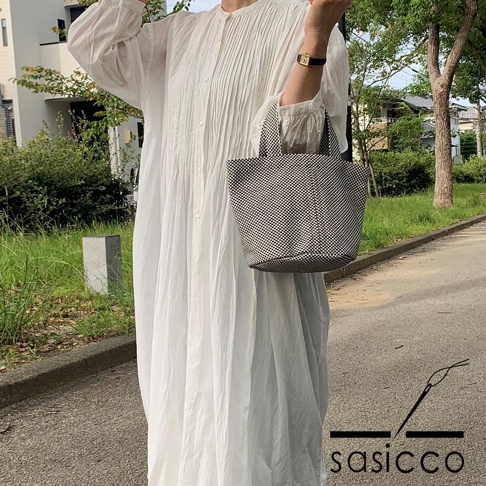 一位女士手持一個黑色和白色格紋圖案的圓底水桶包，包包由三河木綿刺子織製成。