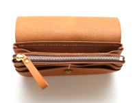 棕色皮革長夾，頂部翻蓋敞開，露出多層次收納空間，內有拉鍊袋，附有皮革拉環和金色拉鍊頭。