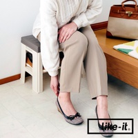 奶油色與灰色塑膠製成的玄關穿鞋收納椅，帶有兩層鞋架空間，可收納一雙鞋子。一位女士穿著米色長褲和格子平底鞋，坐在椅子上。