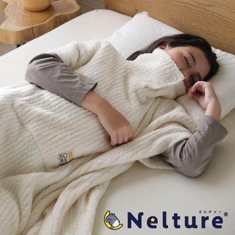 一個穿著白色柔軟斗篷的女孩躺在床上，斗篷上有「Nelture」字樣和可愛的綿羊圖案