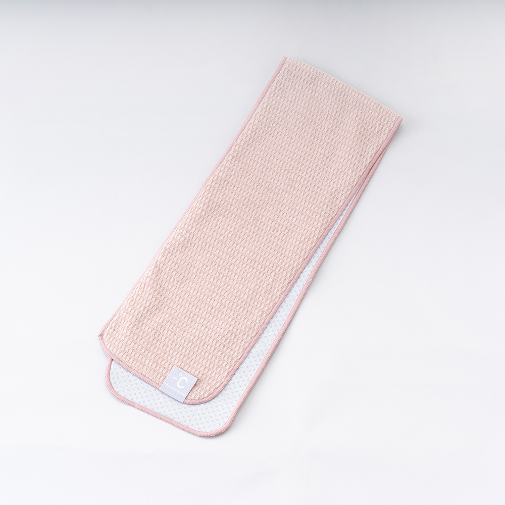 粉色降溫涼感毛巾，表面為細緻的蜂巢格紋織法，另一面為淺灰色網狀材質，帶有白色小圓點圖案。毛巾一角有白色標籤，印有淺灰色 -C 標誌。