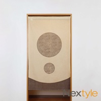 米色布料門簾，中央有兩個深棕色圓形印花，上方圓形較大，下方圓形較小，印花圖案為細密的波浪紋。門簾底部邊緣有波浪形狀，並飾有條狀珠串。