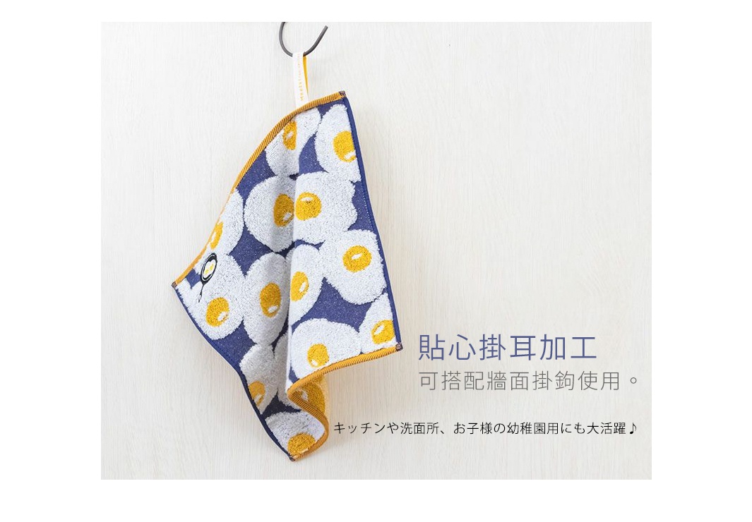 藍色底紋印有白色荷包蛋圖案的提花方巾，掛在牆上的掛鉤上，右側有日文說明。