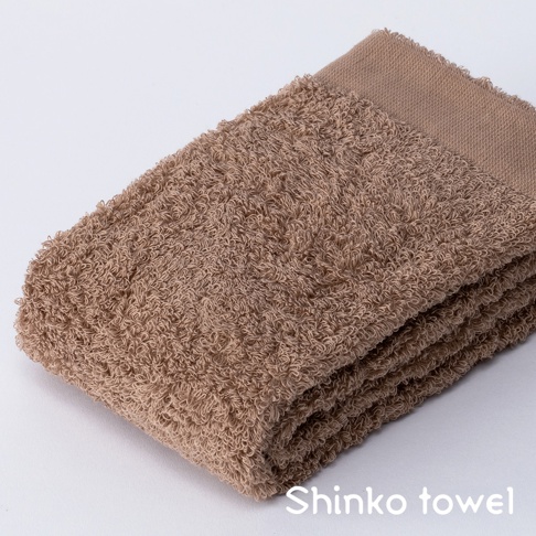 MAISON BLANC 輕奢柔膚匹馬棉毛巾，展現蓬鬆柔軟的紋理，色澤為溫暖的淺褐色，毛巾邊緣帶有細緻的縫線，呈現簡約的設計風格。