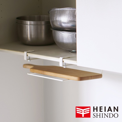 白色金屬製免鑽櫥櫃砧板架，懸掛於櫥櫃層板下方，架上放置一片木質砧板。