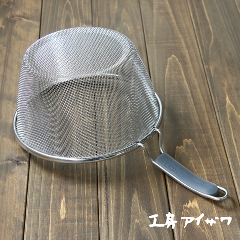 不鏽鋼濾網，網目細緻，搭配灰色矽膠握柄，整體呈銀色，置於木紋桌面。