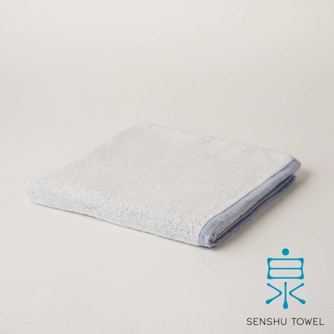 YUKINONE 雪之音柔織有機棉浴巾，呈現柔和的淺藍色滾邊，整體為白色，材質觸感細緻。