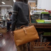 職人手作皮革軟式杜勒斯包，淺棕色皮革，配有頂部提把、可拆卸肩帶及金色金屬釦。