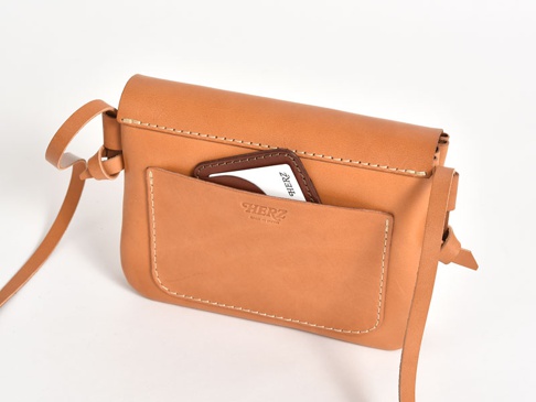 職人手作皮革橫式隨行袋，顏色為淺棕色，材質為真皮。包款設計簡約，設有外置口袋，可放置卡片，並有細緻的縫線裝飾。