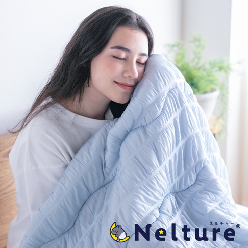 淡藍色單人被，表面有菱格紋縫線，質地輕柔，由一位女子抱著。