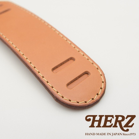 職人手作皮革肩墊，淺棕色牛皮材質，帶有兩道長方形開孔，周圍以米色縫線加固。