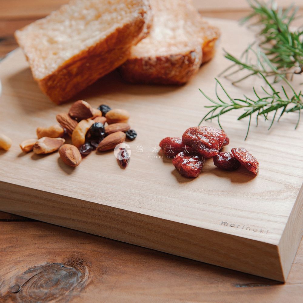 morinoki 榆木砧板上擺放著烤得金黃的吐司、堅果和幾顆紅色的蜜餞，一旁還有迷迭香裝飾。