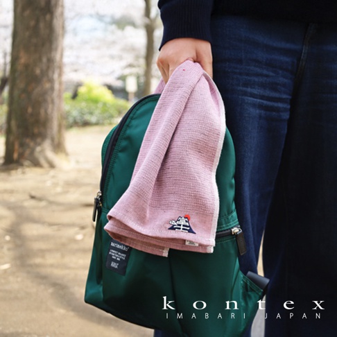 粉色長毛巾，繡有富士山圖案，材質輕薄，搭配綠色背包，背景為戶外公園。